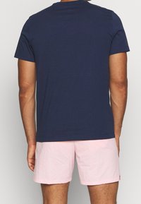 Námořnická modrá bavlněná tričko s kulatým výstřihem. Krátké rukávy a volný střih, doplněné světle růžovými šortkami s texturovanou látkou.