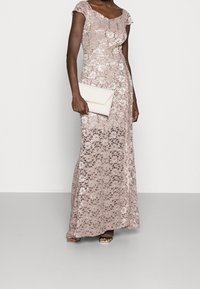 Lång, figurnära aftonklänning i ljusrosalace med blommönster, kapärmar och en slät, draperad bodice. Matchas med en beige clutchtask.