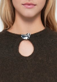 Dunkelbrauner gestrickter Pullover mit einem runden Schlüssel-ausschnitt, verziert mit einer glänzenden silbernen abstrakten Brosche in der Mitte.