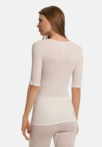 Długi rękaw, ribbed top w miękkim białym materiale, z okrągłym dekoltem i dopasowanym krojem. Rękawy sięgają tuż poniżej łokcia.