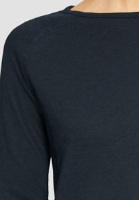 Himmelblaues Langarmoberteil aus Rippstoff, mit Rundhalsausschnitt und Raglanärmeln, das eine weiche, strukturierte Optik aufweist.