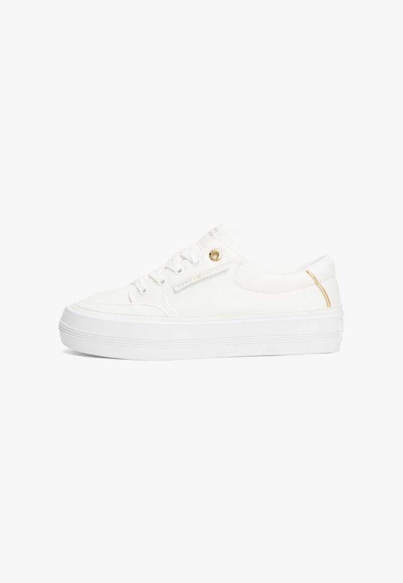 Weiße Leinenschuhe mit einer dicken weißen Sohle, die an der Seite einen kleinen goldenen Akzent und weiße Schnürsenkel haben. Einfaches, niedrig geschnittenes Design.