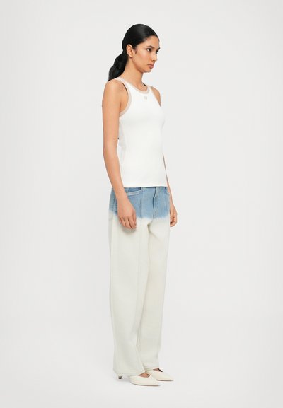 White ribbed tank top paired with light denim, high-waisted, wide-leg pants. Pointed-toe white shoes, smooth texture, casual design.