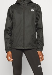 Czarna wodoodporna kurtka z zamkiem błyskawicznym z przodu, regulowanym kapturem i elastycznymi mankietami; posiada logo The North Face na piersi.