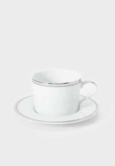 Biała porcelanowa filiżanka ze spodkiem z srebrną obwódką, o gładkim, błyszczącym wykończeniu i z eleganckim uchem na filiżance.