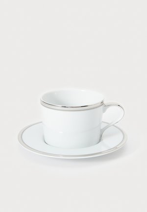 Bílý porcelánový šálek a podšálek se stříbrným okrajem, s hladkým, lesklým povrchem a elegantním uchem na šálku.