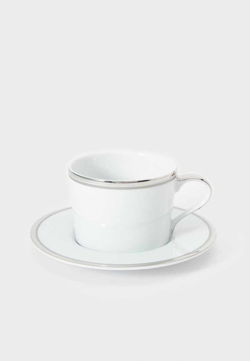 Valge portselanist tass ja taldrik hõbedase servaga, millel on sile, läikiv viimistlus ning tassi peal elegantne käepide.