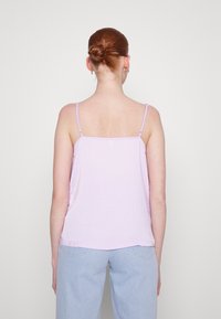 Světle fialový top bez rukávů s tenkými ramínky, vyrobený z měkké, krčila látky. Přímý střih, končí pod pasem, jednoduchý design bez vzorů.