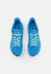 Blauwe sportschoenen met een gestructureerde bovenkant met golfpatronen, contrasterende lichtblauwe veters en een witte zool.