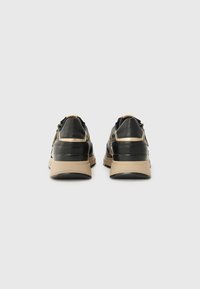 Sorte lærersneakers med beige aksenter, avrundet form, polstret krage og teksturert såle. Har minimalistisk design og subtile hardware detaljer.
