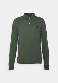 Kardigan s dlouhým rukávem v tmavě zelené bavlně, s klasickým límcem, tříknoflíkovou légou a malým černým logem na hrudi.