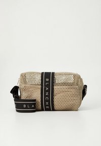 Stačiakampis smėlio spalvos tinklelio kosmetikos krepšys su juodu vertikaliu dirželiu ir nuimamu juodu dirželiu, abiejuose atspausdintas žodis „BLANCHE“.