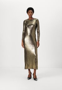 Metalická zlatá dlouhá šatová s elegantním, přiléhavým designem a rovným střihem, která má jemný lesk a měkkou texturu. Podpatky jsou černé se stříbrnými špičkami.