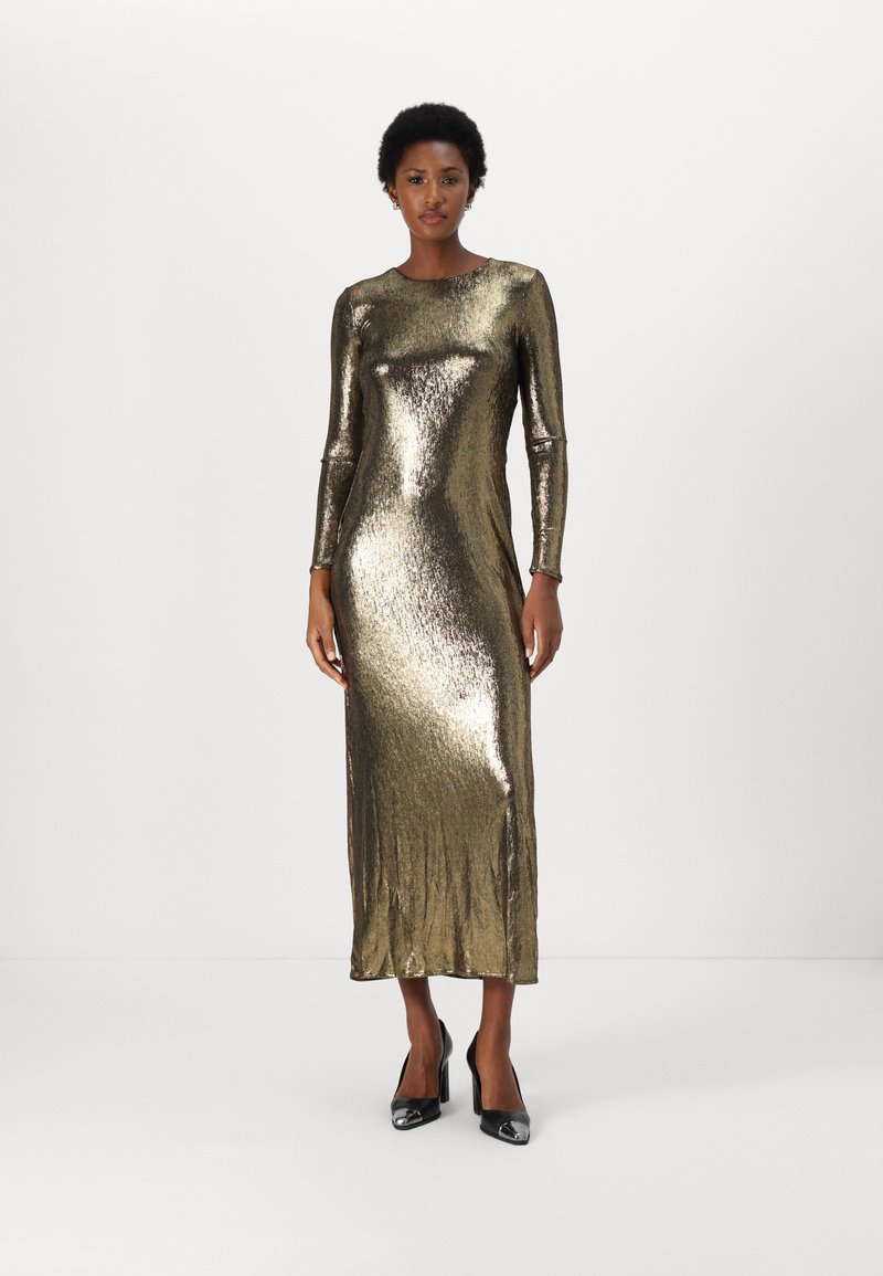 Metalická zlatá dlouhá šatová s elegantním, přiléhavým designem a rovným střihem, která má jemný lesk a měkkou texturu. Podpatky jsou černé se stříbrnými špičkami.