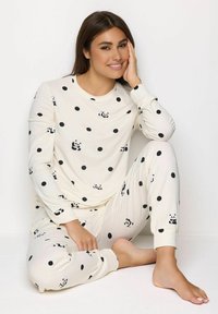 Pigiama color crema con pois neri e piccoli design di panda, realizzati in materiale morbido, con maniche lunghe e polsini alla caviglia.