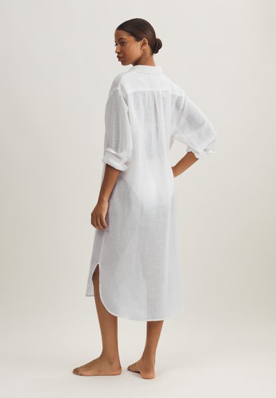 Λευκό φόρεμα πουκάμισο από λινό με γιακά, μανίκια γυρισμένα, πλευρικές σχισμές και άνετη εφαρμογή που φτάνει μέχρι το μέσο της γάμπας. Ελαφρύ ύφασμα.