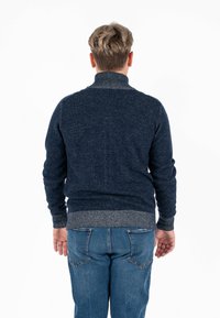 Maglione a maglia blu scuro con colletto alto, caratterizzato da polsini e orlo a costine. La parte posteriore presenta accenti grigi a contrasto sul colletto e sulla vita.