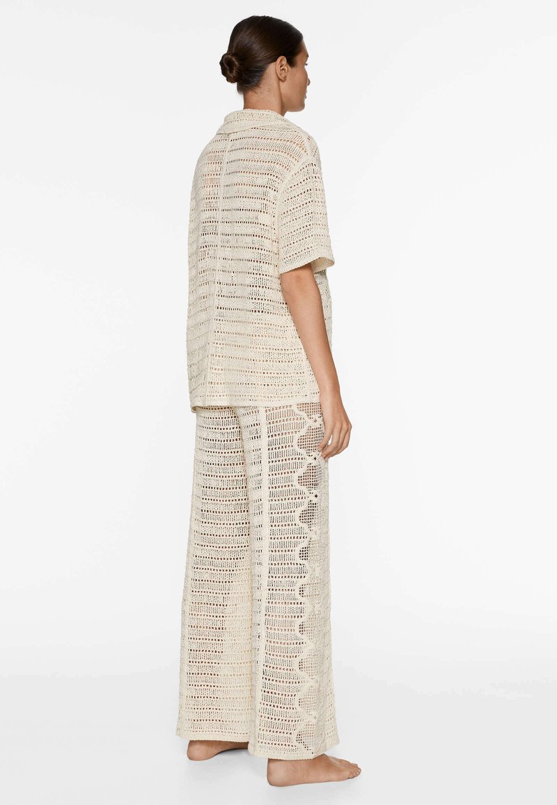 Ensemble léger en crochet crème. Top à manches courtes avec tissage texturé, associé à un pantalon ample avec un détail festonné sur le côté.