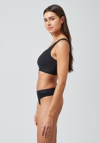Zwarte naadloze bh en bijpassende string, gemaakt van zachte katoenmix. Kenmerken een eenvoudig ontwerp met brede bandjes en een elastische tailleband.