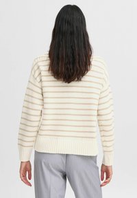 Cremefarbener Strickpullover mit horizontalen beigen Streifen, geripptem Saum und Bündchen, lässiger Passform und mittlerer Dicke. Rückansicht gezeigt.