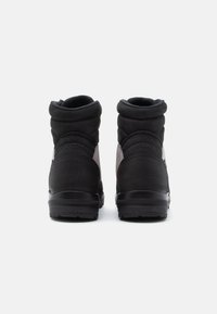 Tênis de cano alto pretos com um cabedal têxtil liso, colarinho acolchoado e detalhes cinza contrastantes nas laterais. Solado de borracha texturizada.