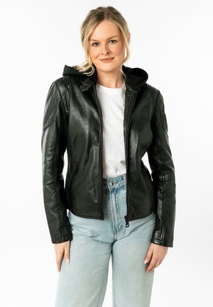 Giacca di pelle nera con chiusura a zip e cappuccio, caratterizzata da un design aderente e un'evidente lavorazione delle cuciture. Indossata con jeans blu chiaro.