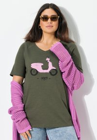 Camiseta verde oliva con cuello en V que presenta un gráfico de una scooter rosa y el texto "1987", combinada con mangas largas de textura rosa.