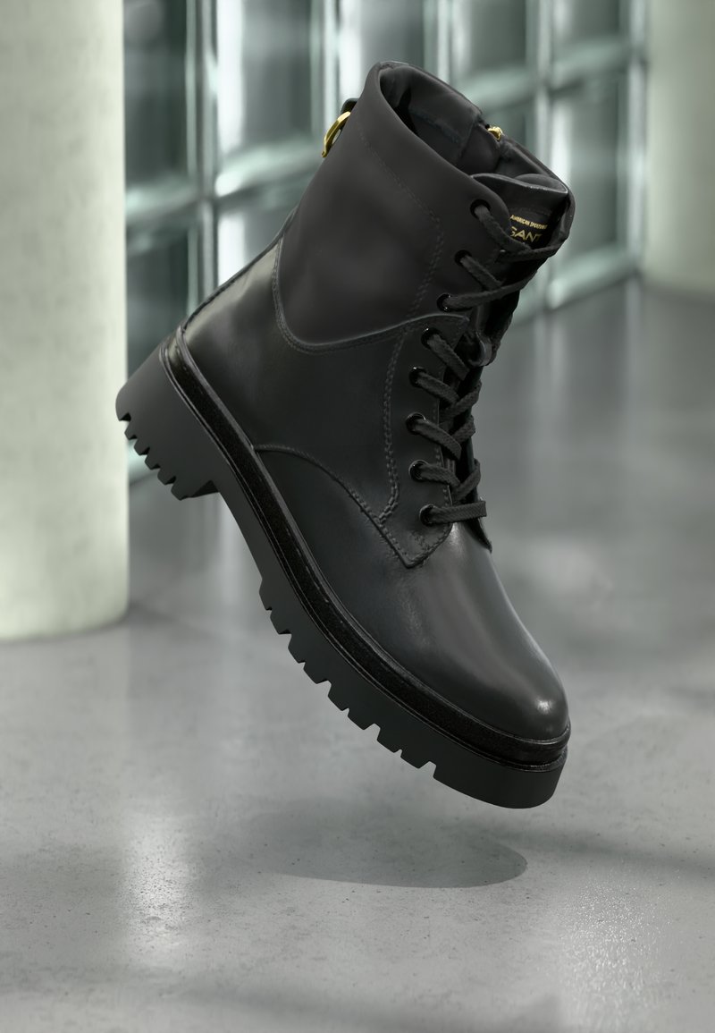 Czarne skórzane botki za kostkę z zapięciem na sznurówki, okrągłym noskiem i masywną gumową podeszwą. Posiada złote akcenty na obcasie.