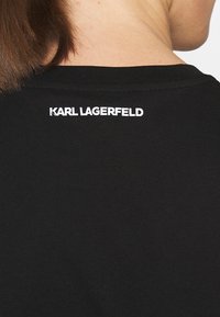 Camiseta de algodón negra con cuello redondo y mangas cortas, con el logo "KARL LAGERFELD" en blanco en la parte superior de la espalda.