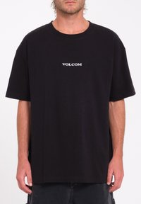 Black cotton t-shirt featuring a white "VOLCOM" logo on the chest, short sleeves, and a relaxed fit with a straight hem.