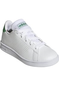 Zapatilla de cuero blanco con acentos verdes, detalles perforados en los laterales, cordones blancos y suela de goma texturizada. Logo destacado en la lengua.