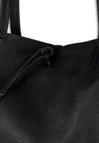 Zwarte leren tote bag met een gestructureerd oppervlak, voorzien van een trekkoordsluiting en dubbele schouderbanden. Eenvoudig en functioneel ontwerp.