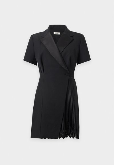 Robe blazer noire à manches courtes avec revers en satin, fermeture par un bouton et panneau plissé avec bordure en dentelle sur un côté.