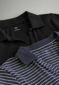Zwei polohemden mit Kragen: eines einfarbig schwarz und das andere dunkelblau mit weißen Streifen. Beide haben Etiketten in der Nähe des Kragens.