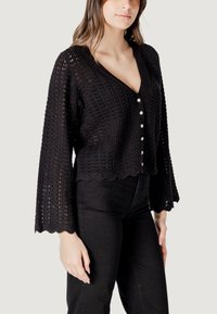 Cardigan noir en crochet avec des manches évasées, un ourlet festonné et six boutons décoratifs sur le devant. Texture légère et tricotée à jour.