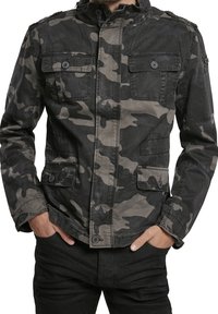 Kamouflage-mönstrad jacka i nyanser av grått och svart, med hög krage, knappar och fyra fickor. Tillverkad av slitstarkt tyg.