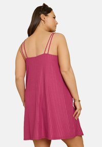 Fuchsia ärmlös klänning med ribbad textur, med tunna korskorsade remmar och en avslappnad passform som vidgar sig vid fållen.
