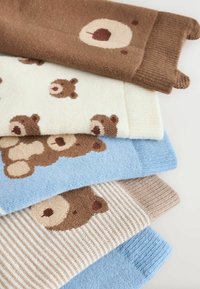 Sæt med fem par strikkede sokker i beige, brun og blå. Mønstrene har bjørneansigt; et par har striber. Blød tekstur og varierede design.