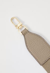 Sangle en cuir de couleur gris clair avec une finition texturée, dotée d'un clip en métal doré et de bords lisses pour l'attache.