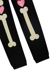 Czarne dresy z dużymi, świecącymi wzorami kości w beżowych i różowych sercach, z elastycznymi mankietami i miękką teksturą.