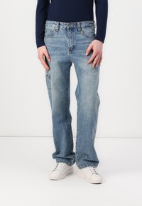 Lyseblå denim jeans med en afslappet pasform, der har front- og sidelommer samt en diskret falmeeffekt. Stylet med hvide sneakers.