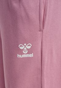 Roze katoenen joggers met een gestructureerde afwerking, voorzien van een wit logo. Het ontwerp heeft zijzakken en een ontspannen pasvorm.
