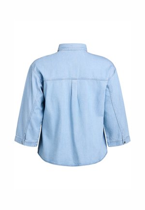 Světle modrá denimová košile s límečkem, tříčtvrtečními rukávy a záhybem na zádech. Má knoflíkové detaily na manžetách rukávů.