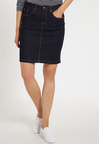 Falda lápiz de mezclilla oscura con longitud hasta mitad del muslo, con costuras doradas, diseño de cinco bolsillos y cierre de botón en la parte frontal.