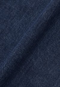 Denim w głębokim granatowym kolorze, o gładkiej fakturze z delikatnym wzorem tkaniny i niewielkimi różnicami w odcieniach.