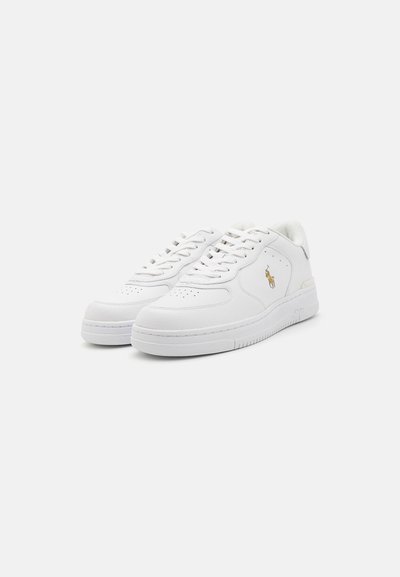 Zapatillas de cuero blancas con puntera perforada, cordones planos y sutiles detalles del logo. Cuentan con una suela de goma y un cuello acolchado para mayor comodidad.