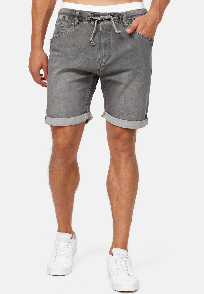 Shorts en denim gris avec une taille à cordon, des ourlets roulés, des poches latérales et une texture subtile. Assortis avec des baskets blanches.