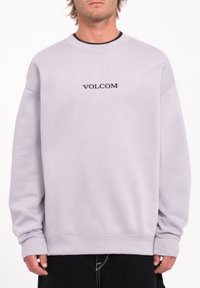 Sudadera de color gris claro con cuello redondo y corte holgado. Logo "VOLCOM" exhibido en negro en el centro. Puños y dobladillo acanalados.