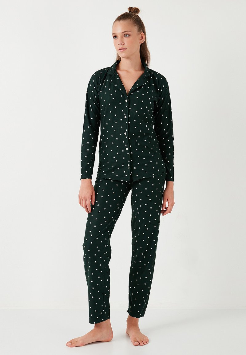 Ensemble de pyjama vert foncé en tissu doux, avec des motifs d'étoiles blanches, manches longues et chemise à boutons avec pantalons assortis.
