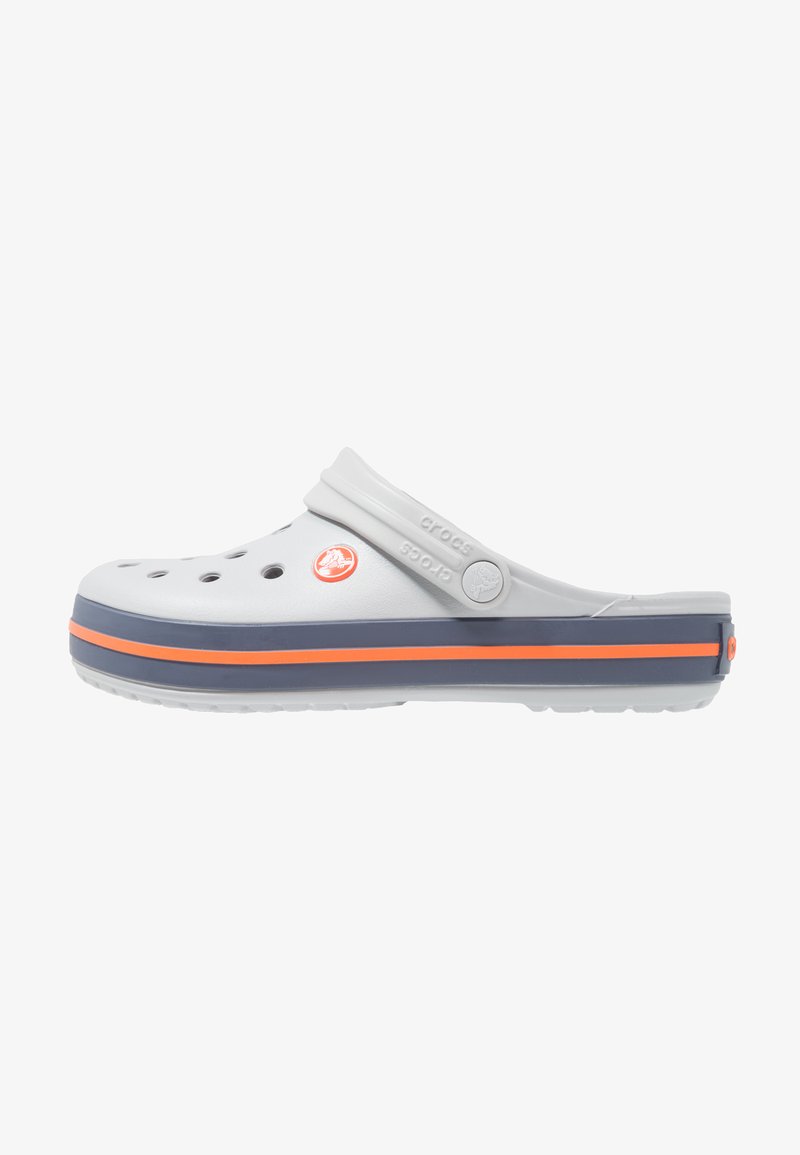 Hvide clogs i crocs-stil med ventilationshuller, grå bånd og orange stribe, lavet af letvægtsmateriale, med justerbar rygstrop.